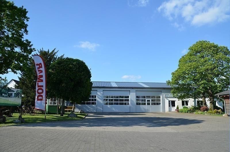 Industriegebäude mit großen Fenstern und einer roten Flagge unter blauem Himmel.