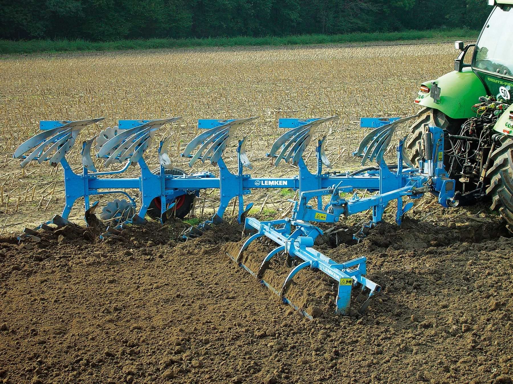 An einem Traktor befestigter Pflug bei der Bodenbearbeitung auf einem Feld.